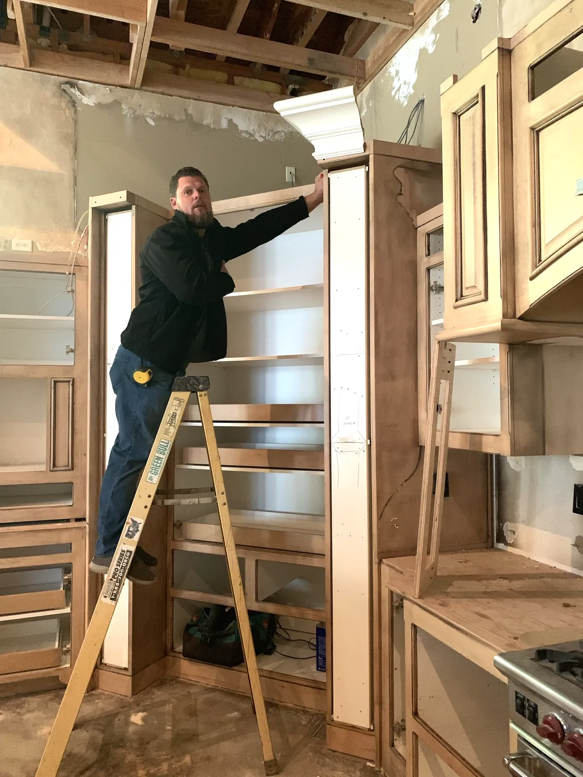 Andrey Voronenko fitting crown moulding on custom cabinetry during a kitchen install