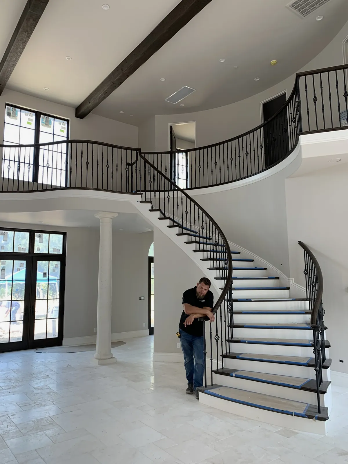 Andrey Voronenko beside a curved staircase railing during an estate home install