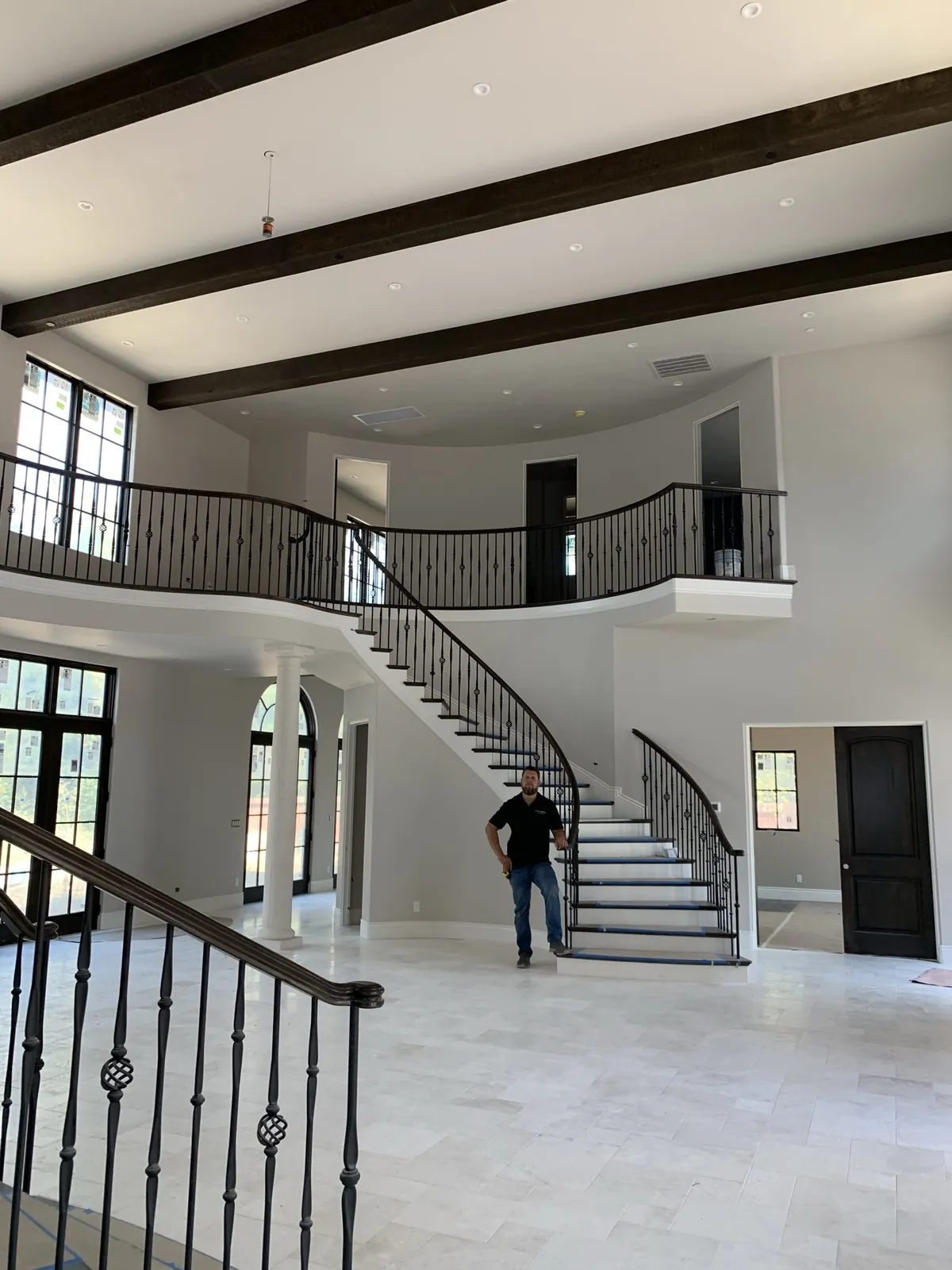 Andrey Voronenko on site in a two-story estate foyer with a curved staircase