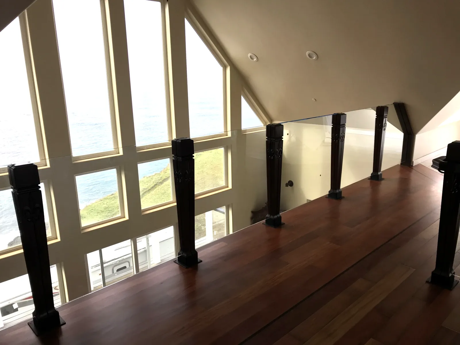 Custom carved wood railing posts with glass panels in an estate loft