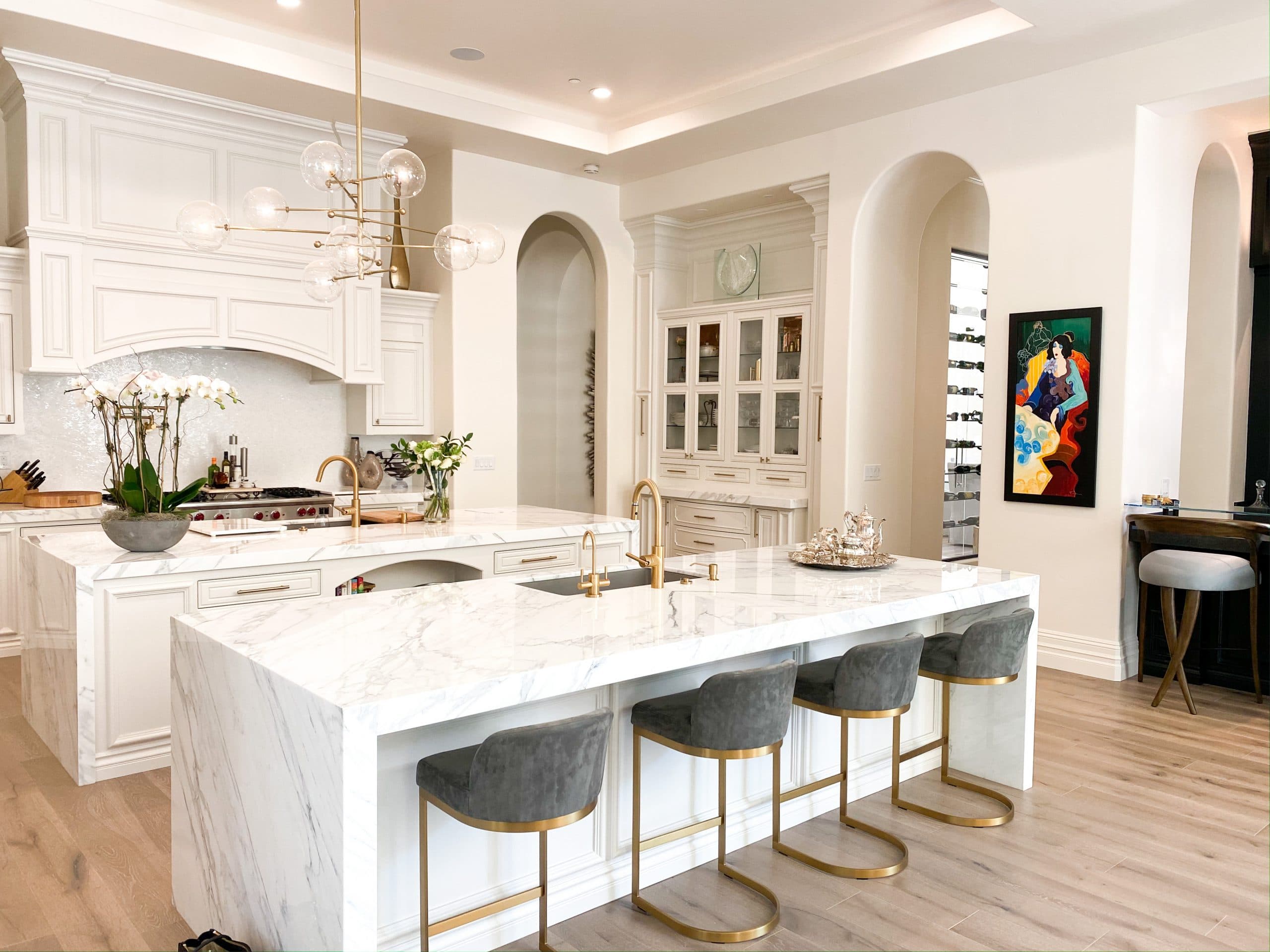 Custom white estate kitchen with arched cabinet openings and a marble island
